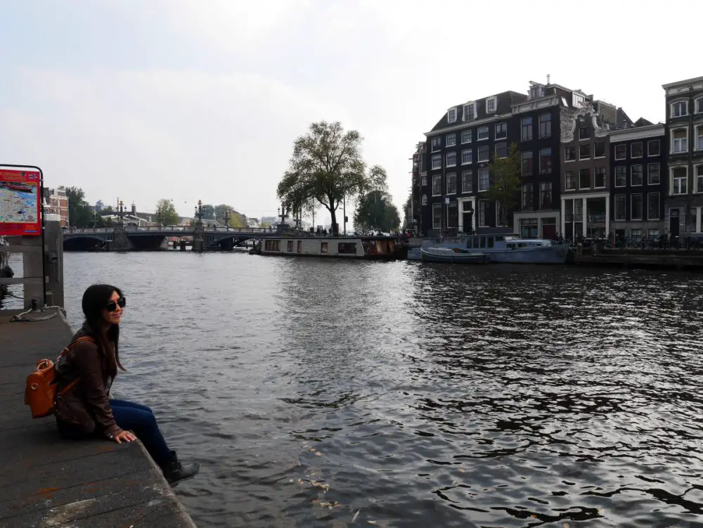 Me sitting by the peaceful canal in Amsterdam, Netherlands| Laugh Travel Eat