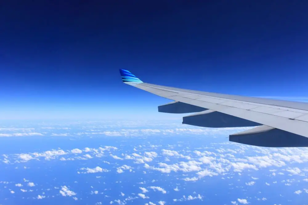Looking out at the sky and airplane wing mid-flight| Laugh Travel Eat
