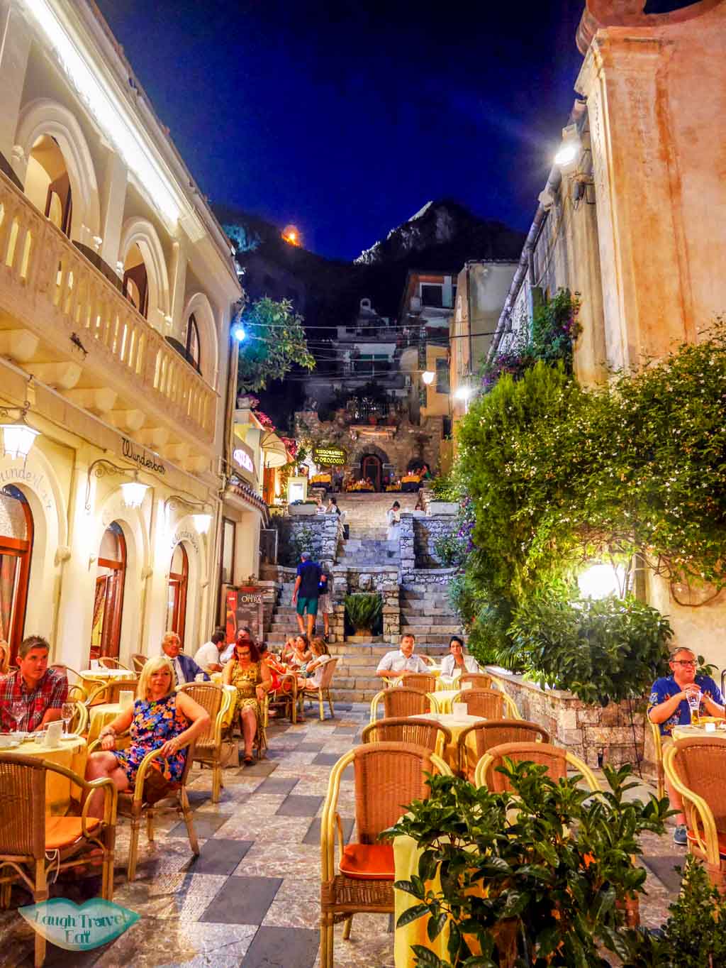 One of the many side streets in Taormina, ever so lively with restaurant tables filling up 2/3 of the street | Laugh Travel Eat