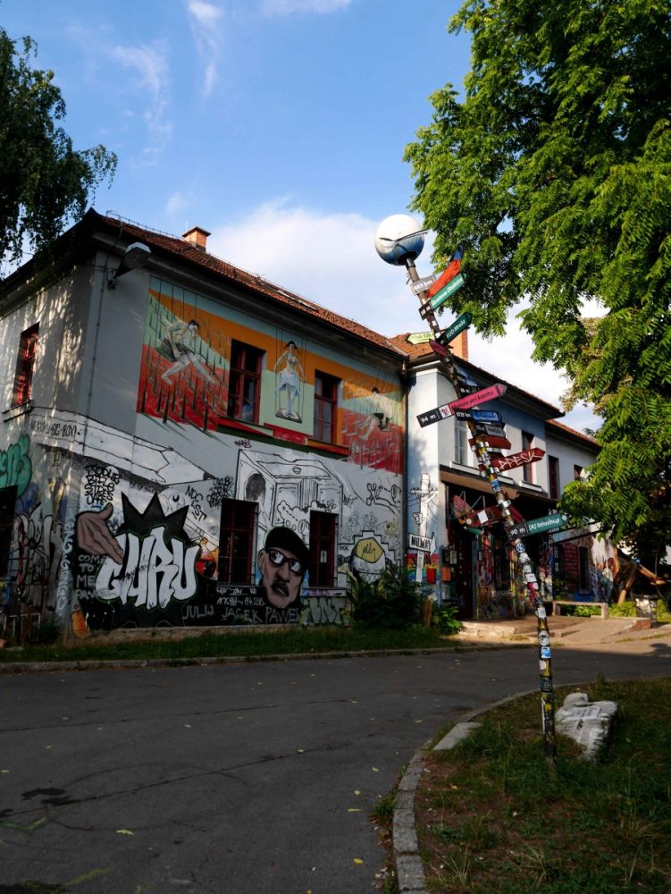 titled lamppost colourfully decorated in stickers and post signs in Metelkova, Ljubljana | Laugh Travel Eat