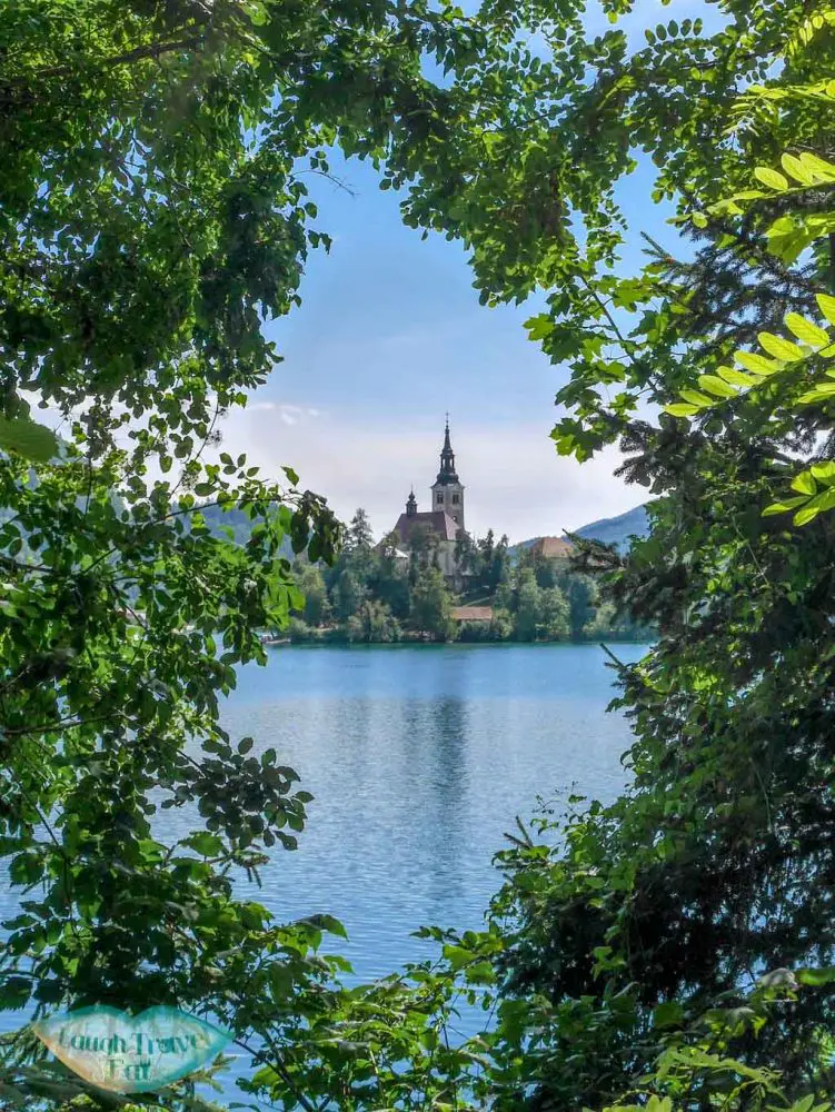 Bled island through trees at Bled | Laugh Travel Eat