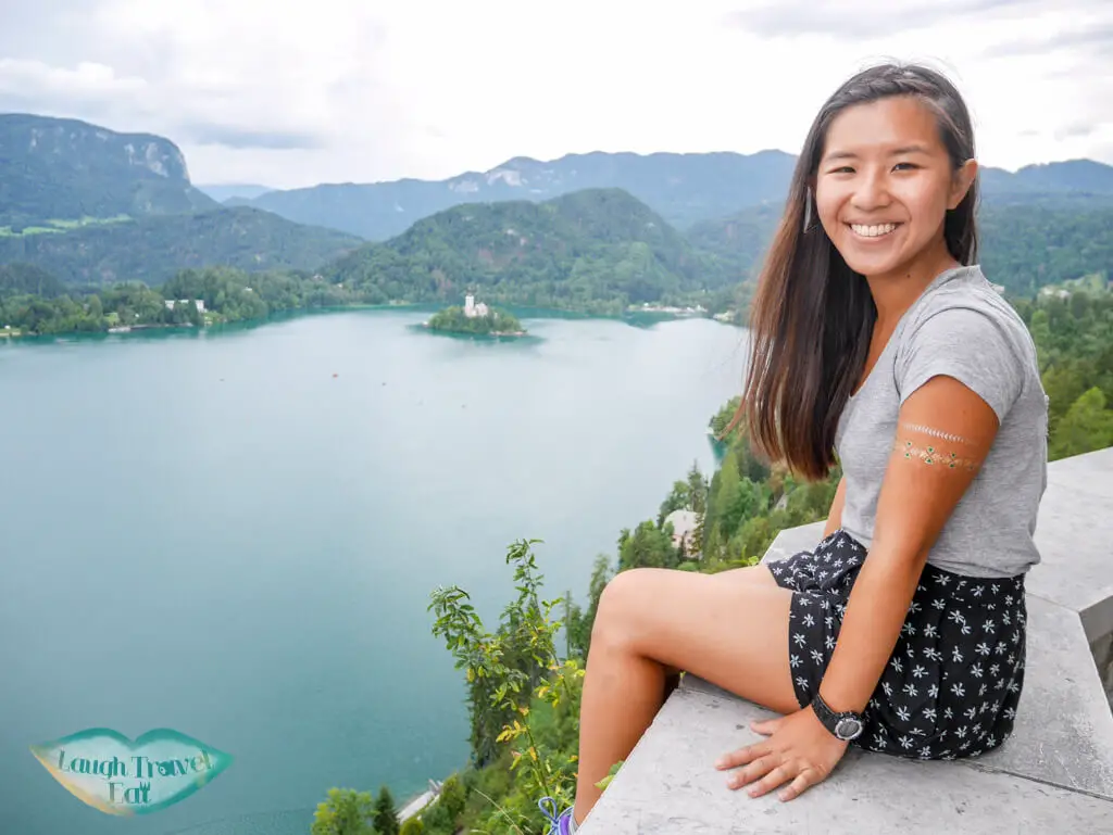 Me sitting on the wall of Bled Castle looking down to Lake Bled | Laugh Travel Eat