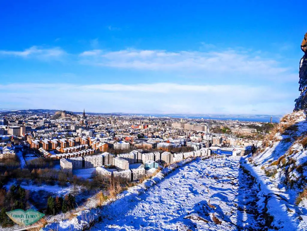 On the way down from Arthur's seat through the snow-covered path, with houses within site - Laugh Travel Eat
