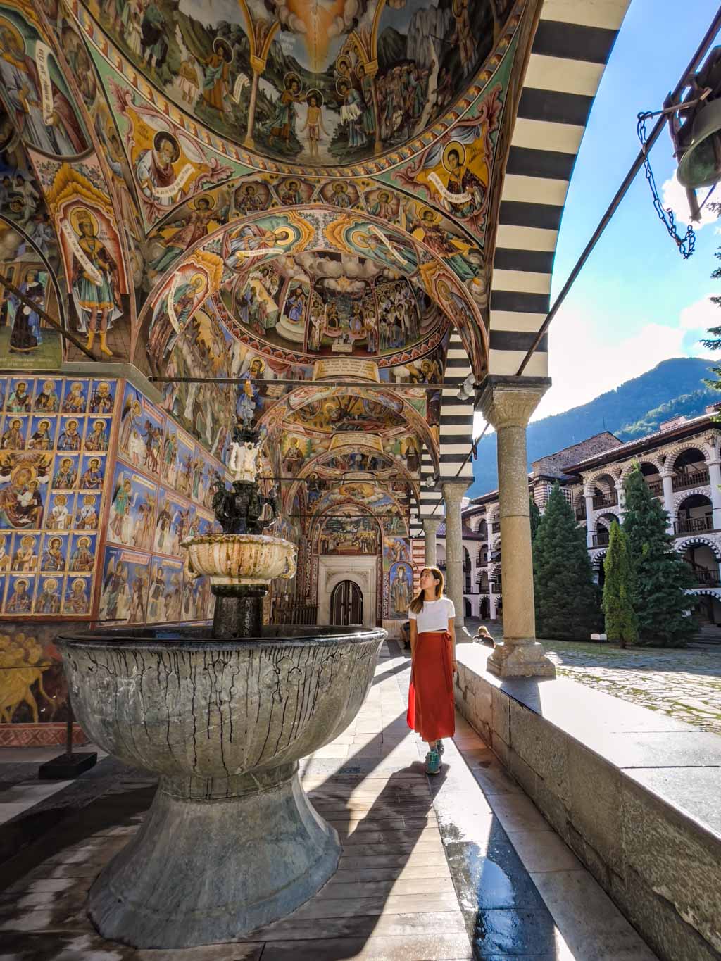 girl at photospot in front of murals on church wall rila monastery from sofia bulgaria - laugh travel eat-2