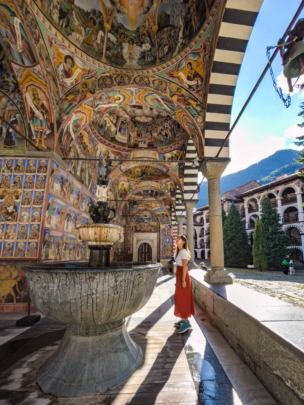 girl at photospot in front of murals on church wall rila monastery from sofia bulgaria - laugh travel eat-2